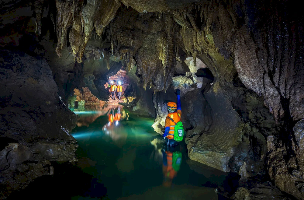 Explorers rely on headlamps to navigate narrow passages, underground streams, offering an authentic caving experience